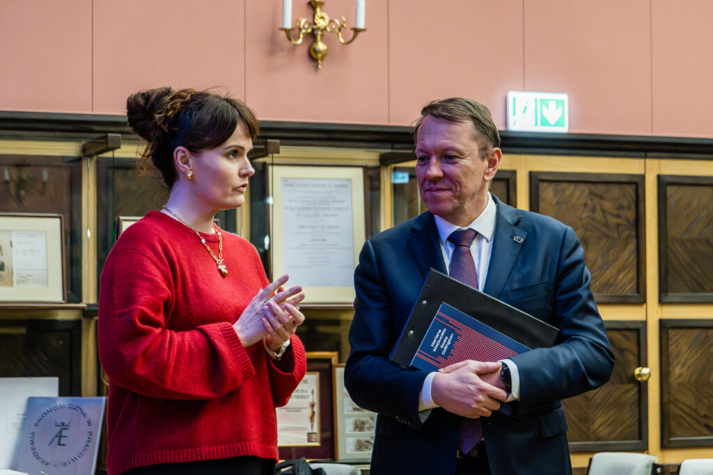 kobieta w czerwieni i mężczyzna w garniturze w sali UEK