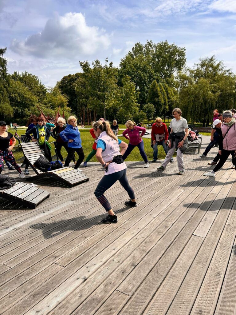 Na zdjęciu grupa osób wykonujących ćwiczenia rozciągające pod okiem Instruktorki Slow Joggingu
