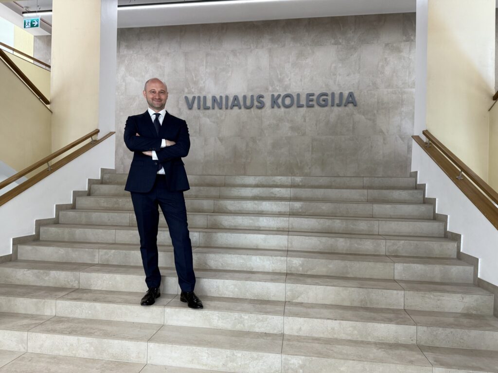 Mężczyzna w garniturze, stoi na schodach w budynku