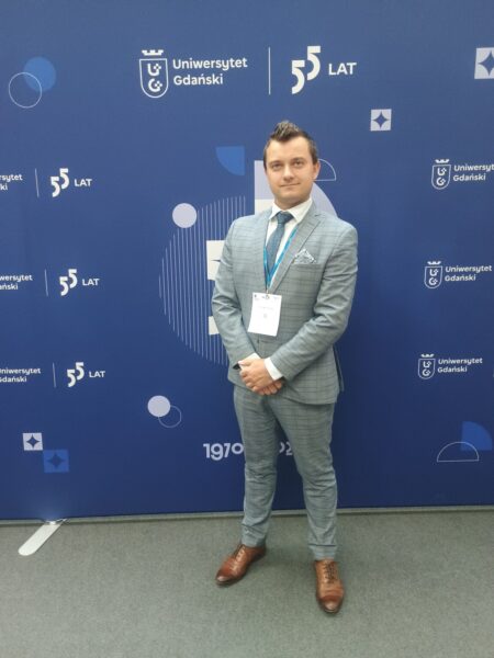 Mężczyzna w garniturze na tle ścianki ze sponsorami